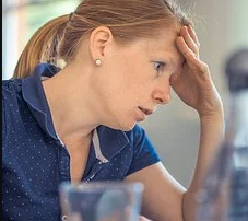 Annoyed Woman sitting with hand on forehead